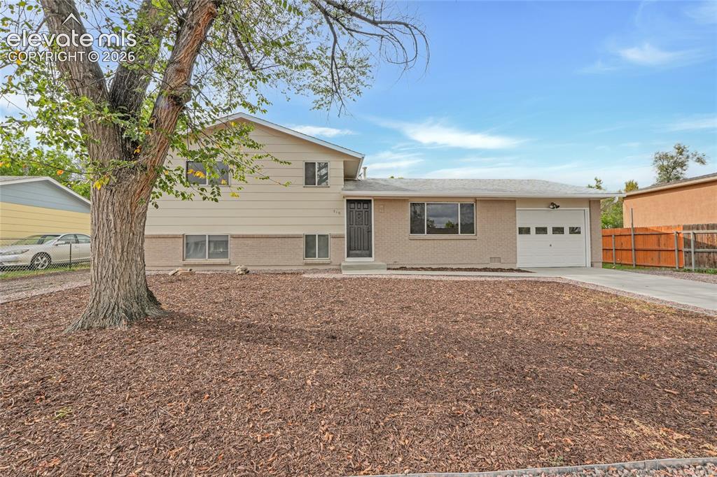 Caption: Exterior featuring light-colored siding, brick accents, an attached garage, and a concrete driveway
