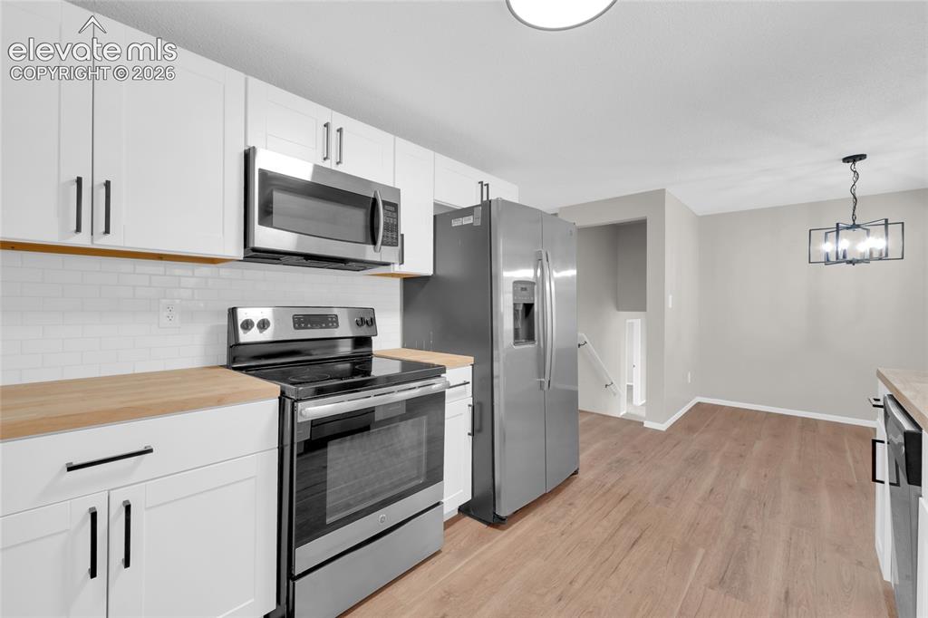 Image 10 of 29: Kitchen featuring white cabinetry, wood-finish countertops, stainless steel
