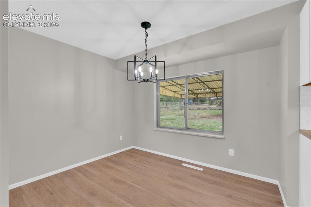 Image 11 of 29: Wood-finish flooring, contemporary black chandelier, neutral wall tones, an