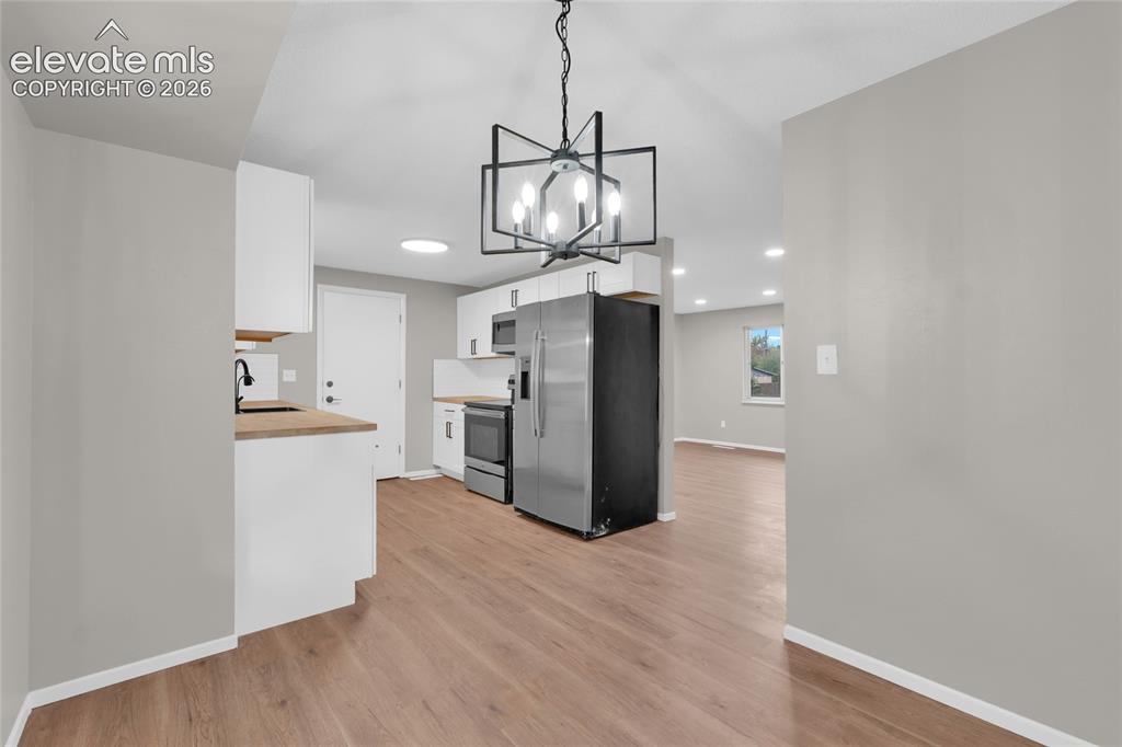 Image 12 of 29: Kitchen featuring wood-finish flooring, white cabinetry, stainless steel ap