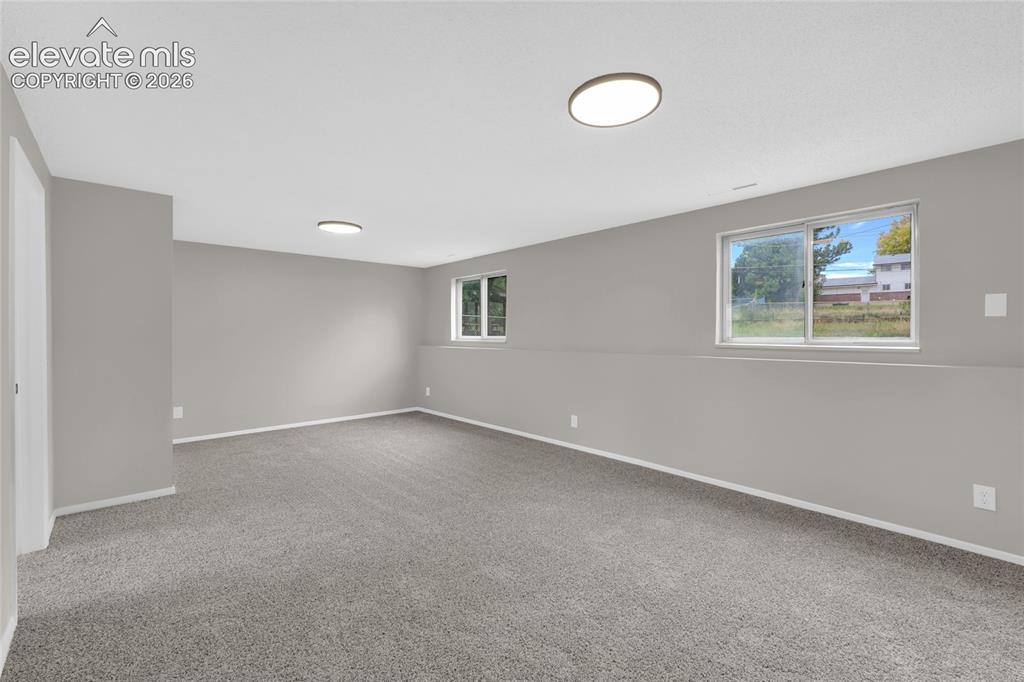 Image 14 of 29: Spacious room featuring neutral carpeting, light gray walls, and two flush-
