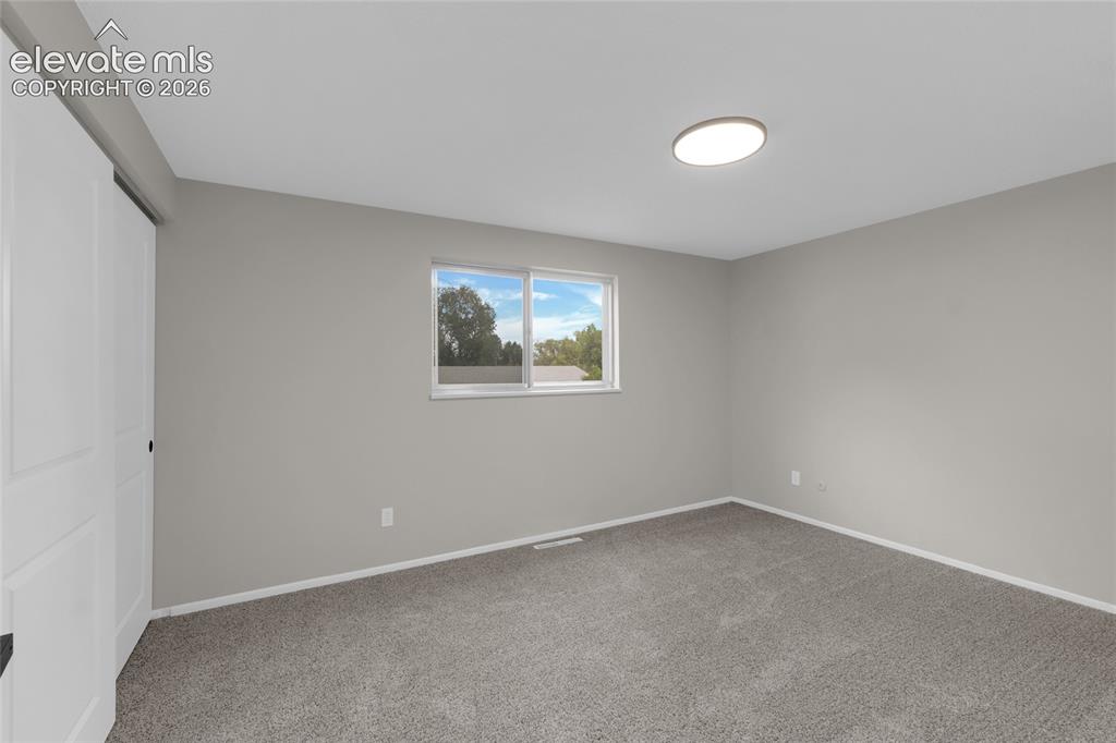 Image 18 of 29: Neutral gray painted walls, window with white trim, gray carpet flooring, w