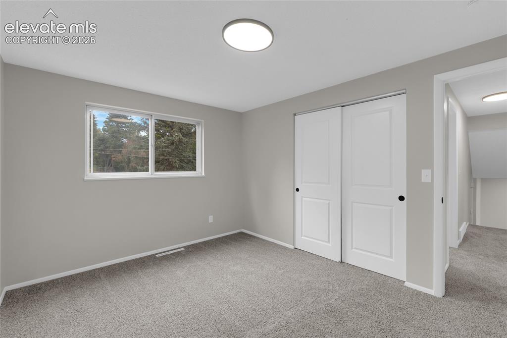 Image 22 of 29: Neutral gray walls with white trim, gray carpeting, dual white sliding clos