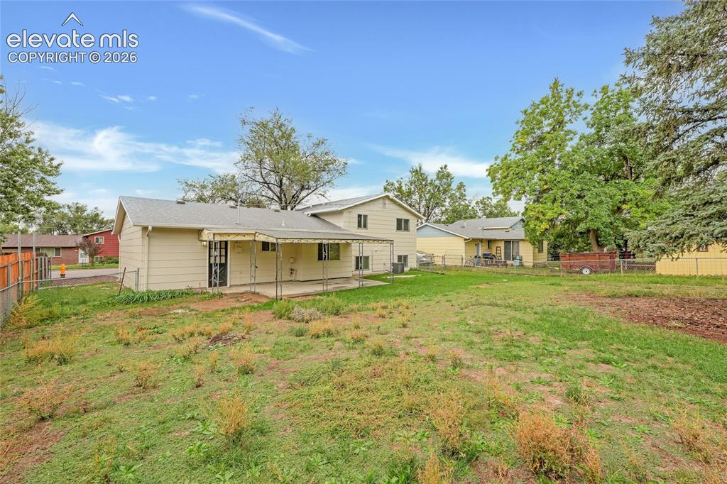 Image 28 of 29: Expansive rear yard with a fenced perimeter and mature trees
