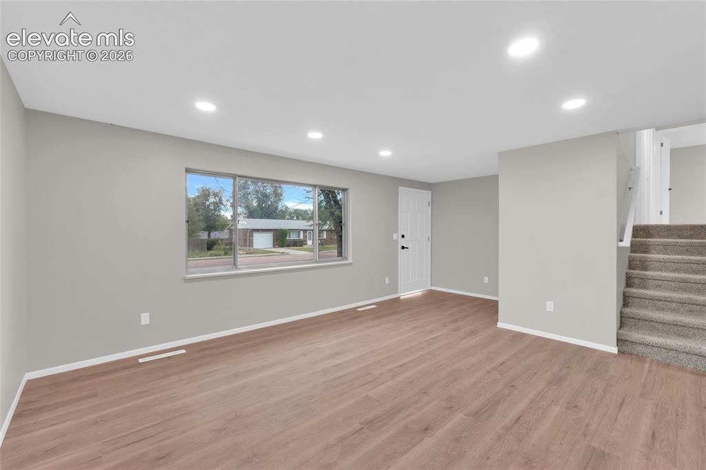 Image 6 of 29: Recessed lighting, wood-finish flooring, light gray wall paint, and white t