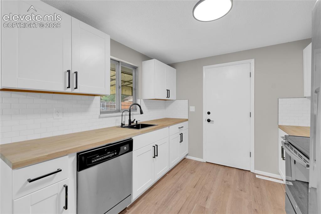 Image 7 of 29: White shaker-style cabinetry with matte black hardware, wood-finish counter