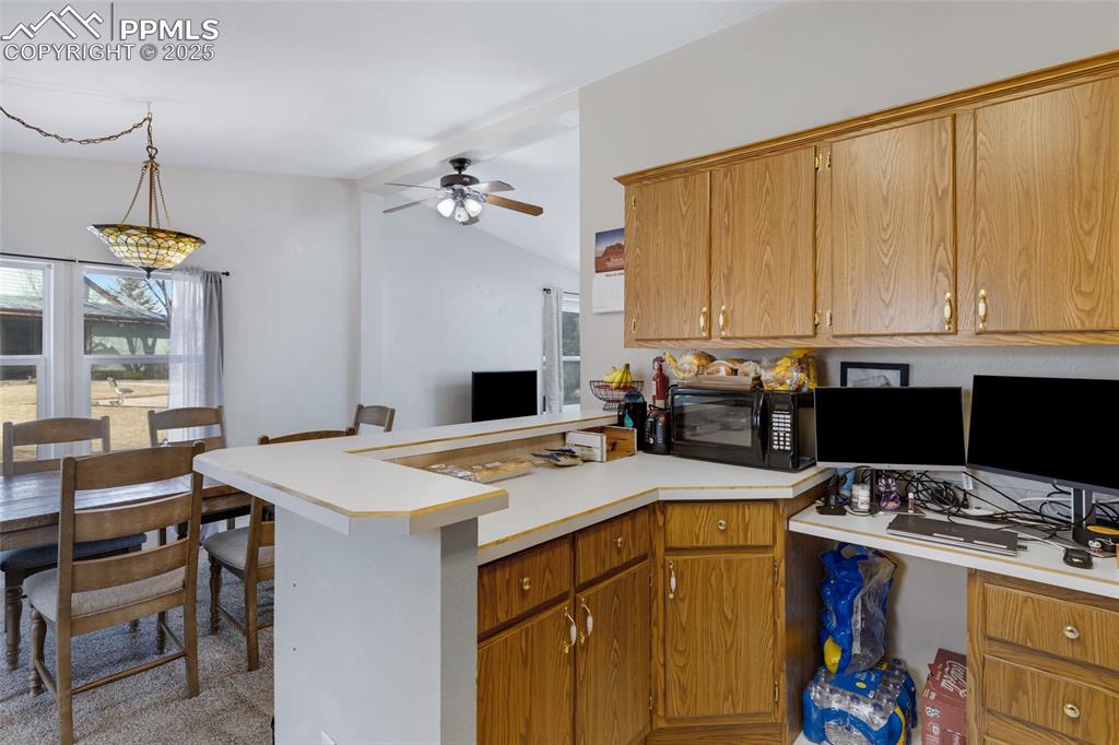Image 12 of 24: Kitchen featuring light countertops, a peninsula, a ceiling fan, lofted cei