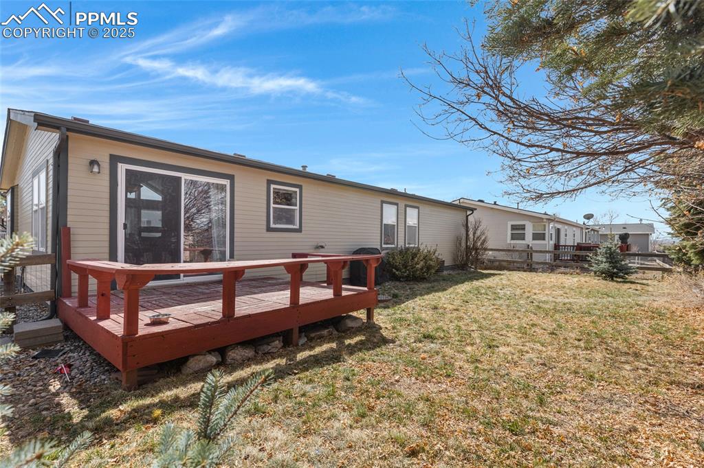 Image 21 of 24: Rear view of property featuring a wooden deck and a lawn