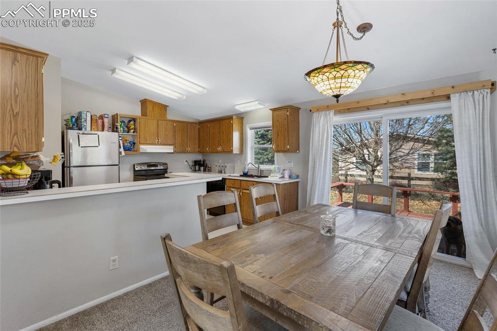 Image 8 of 24: Dining space with baseboards, vaulted ceiling, and light carpet
