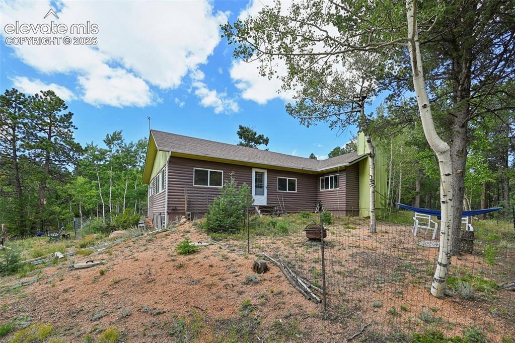 Caption: Wood-sided exterior with a sloped roofline, surrounded by mature trees