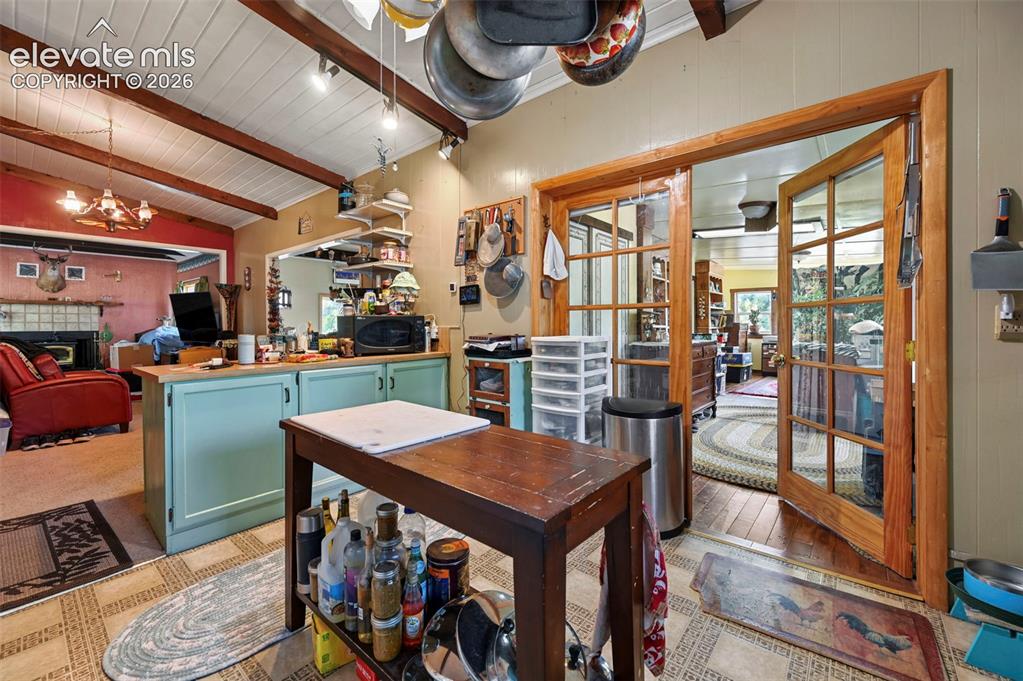 Image 10 of 29: Kitchen featuring a wood-finish countertop island with cabinetry, exposed w