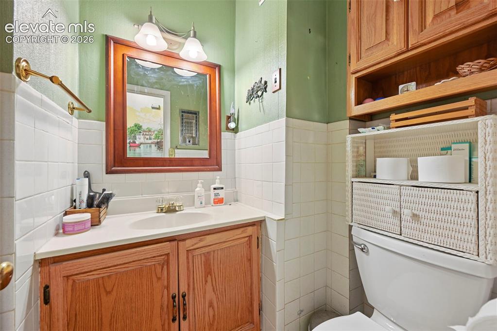 Image 12 of 29: Wood-finish vanity with a single basin sink and dual-handle faucet