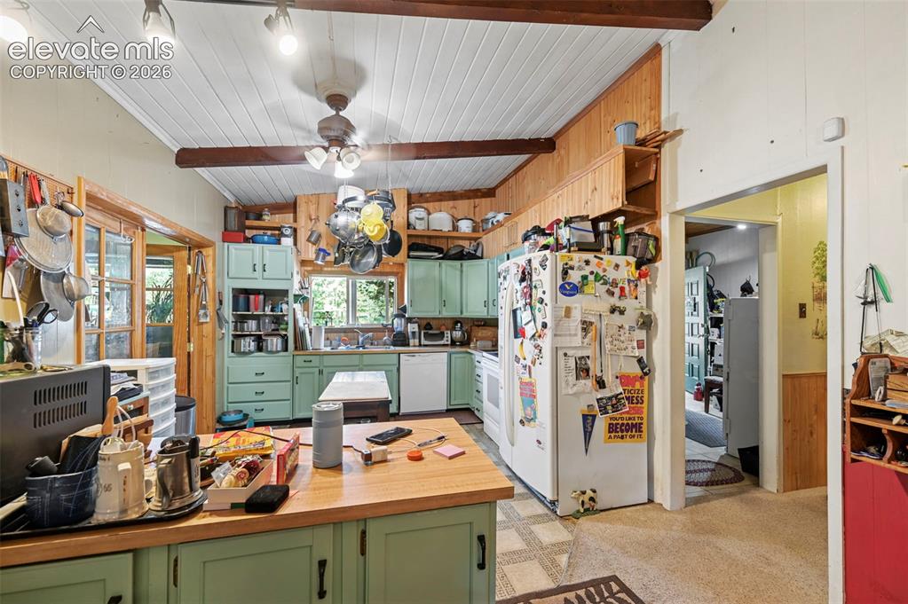 Image 15 of 29: Vaulted ceiling with exposed wood beams, wood-finish cabinetry, built-in sh