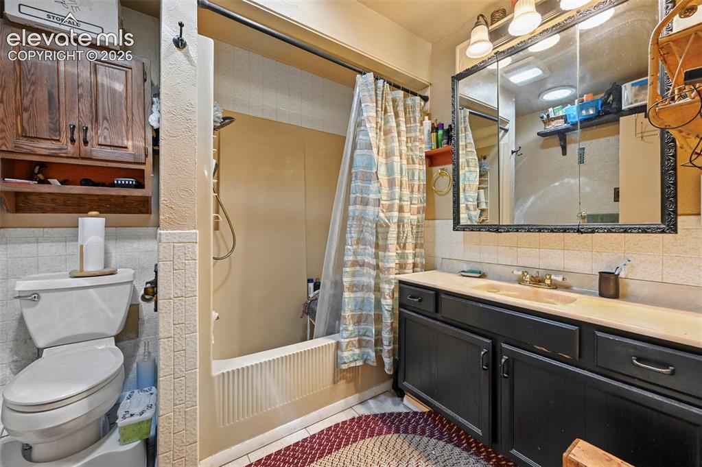 Image 4 of 29: Built-in shower/tub combination with a wall-mounted shower head, vanity wit