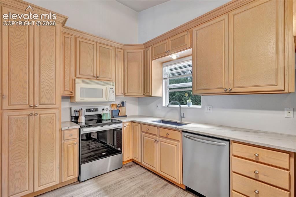Image 12 of 44: Kitchen featuring extensive light wood-finish cabinetry, stainless steel ap