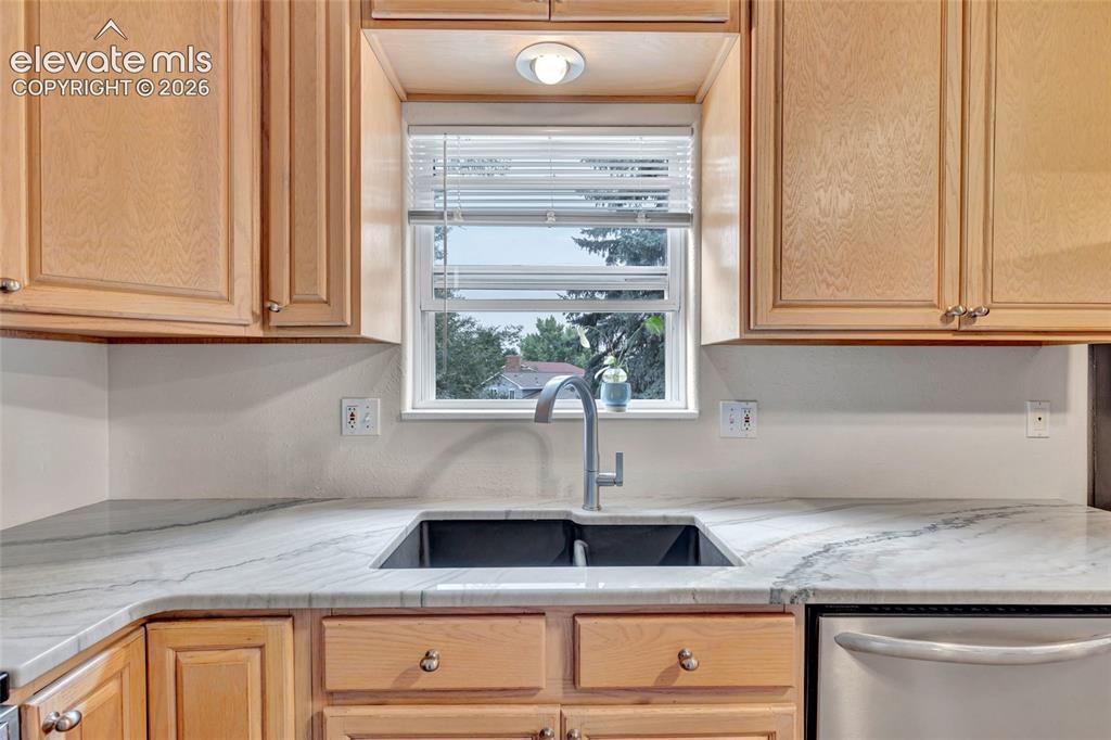 Image 13 of 44: Kitchen with wood cabinetry, light-toned countertops, undermount sink with