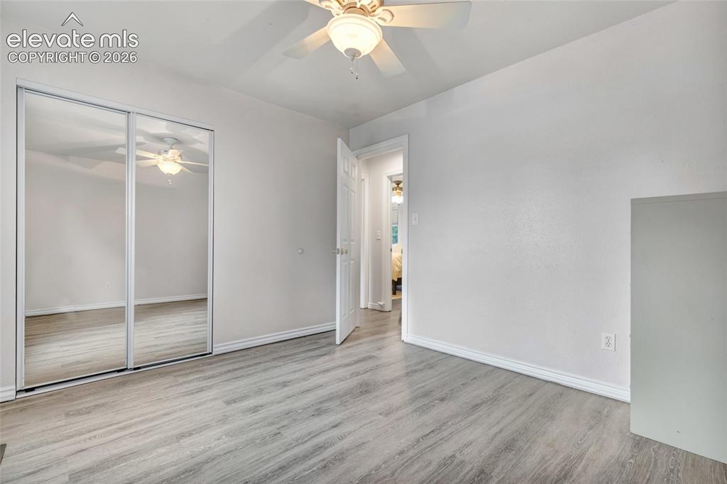 Image 17 of 44: Room with wood-finish flooring, white walls, and a ceiling fan with light f