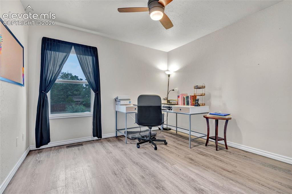 Image 18 of 44: Spacious room featuring wood-finish flooring, a ceiling fan with integrated