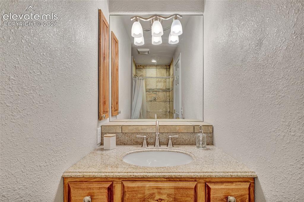 Image 19 of 44: Vanity featuring a built-in sink, granite countertop, and wood-finish cabin