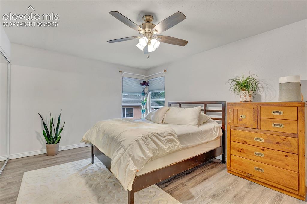 Image 21 of 44: Bedroom featuring wood-finish flooring, a corner window, and a ceiling fan