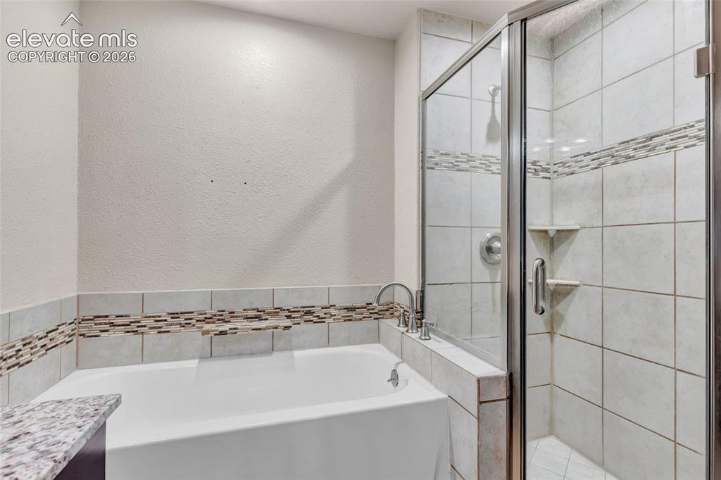 Image 24 of 44: Soaking tub with deck-mounted faucet, complemented by a tiled shower enclos