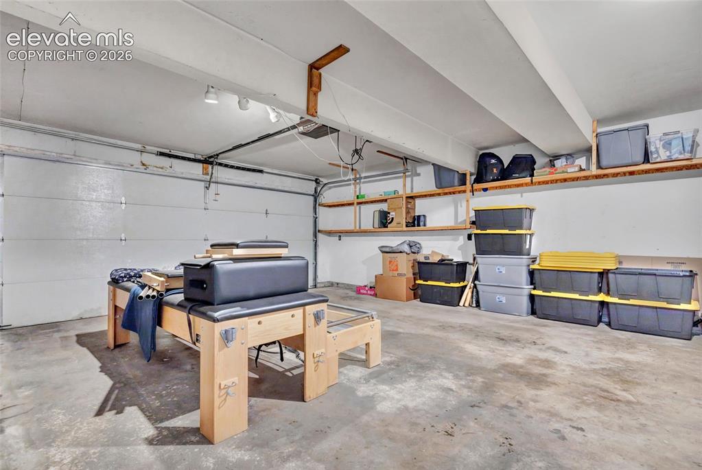 Image 31 of 44: Spacious garage featuring a concrete floor, built-in overhead shelving, and