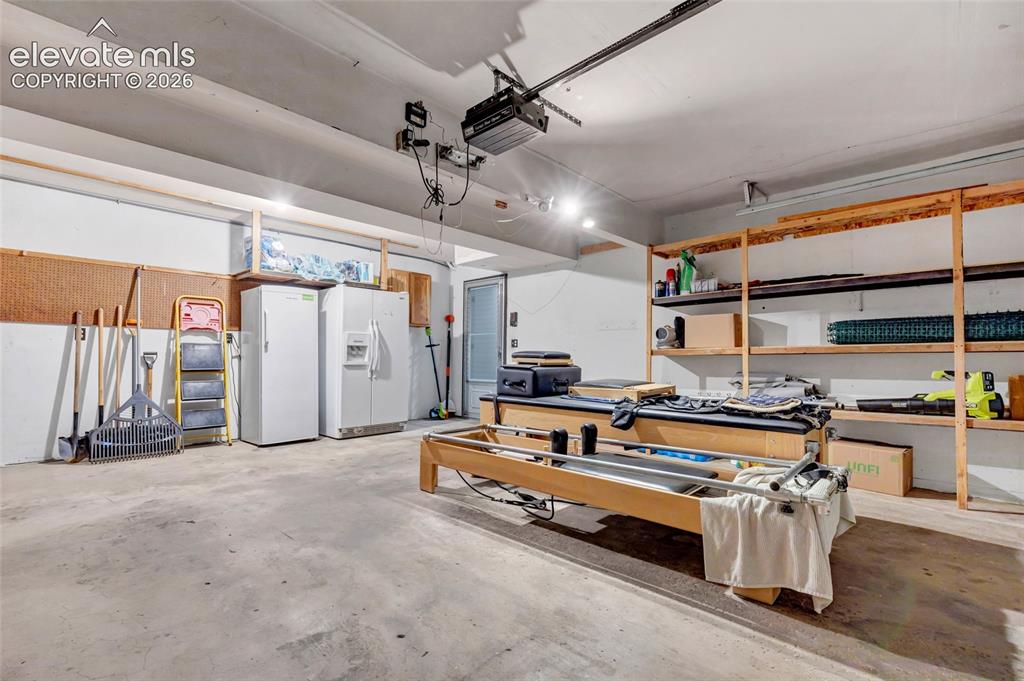 Image 32 of 44: Spacious garage featuring a concrete floor, overhead lighting, garage door