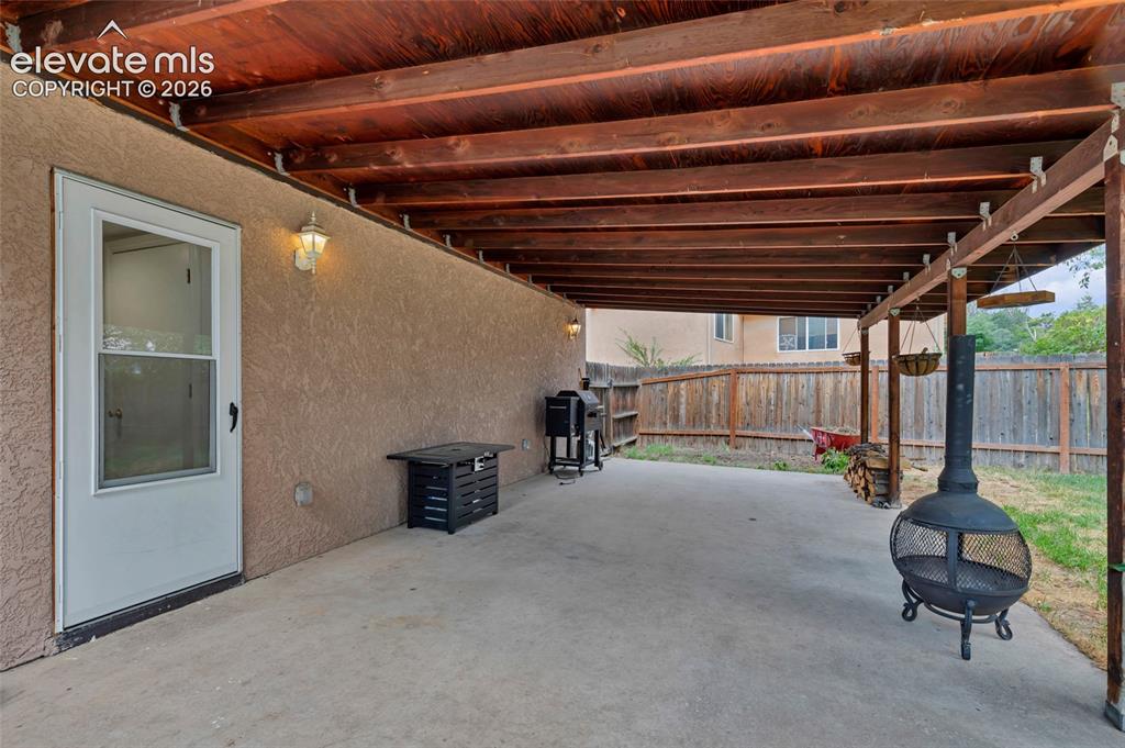 Image 33 of 44: Covered patio with a concrete surface and exposed wood beam ceiling