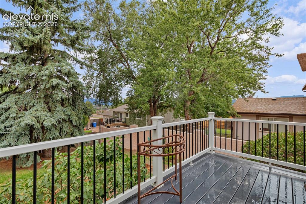 Image 34 of 44: Outdoor deck featuring dark composite decking, white railing with black bal