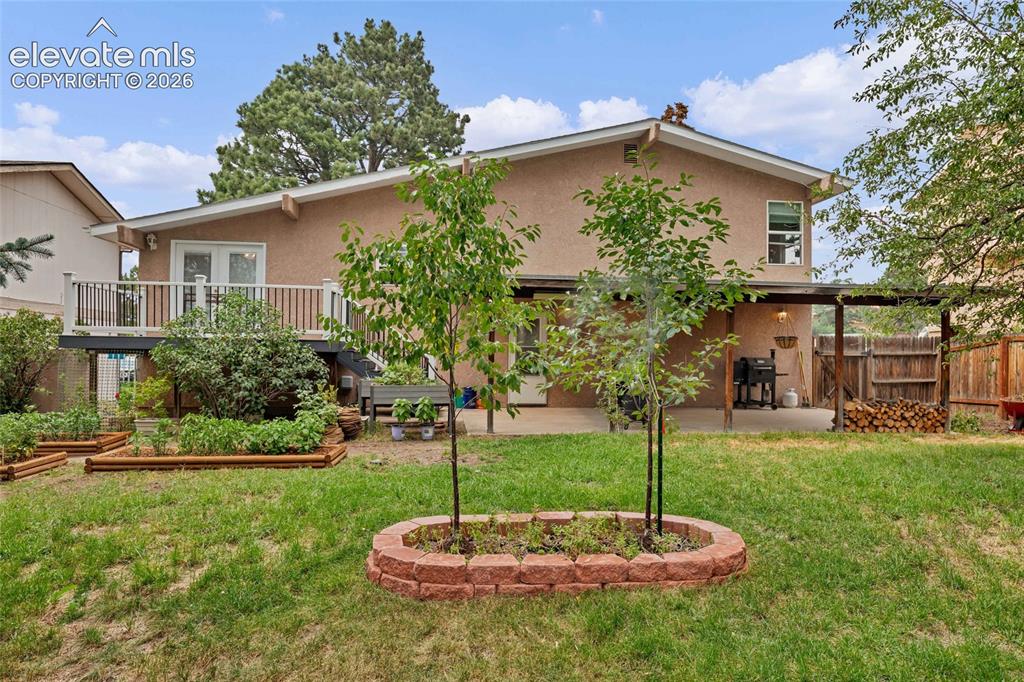 Image 37 of 44: Expansive backyard featuring a stucco exterior, raised deck with white rail