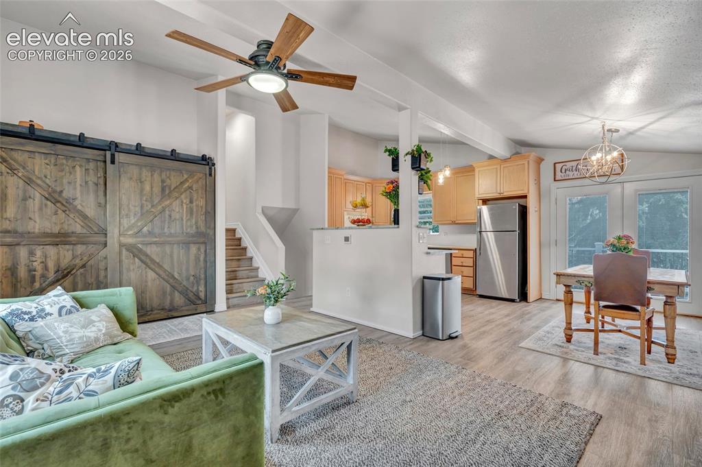 Image 8 of 44: Open-concept living area featuring wood-finish flooring, a contemporary cei