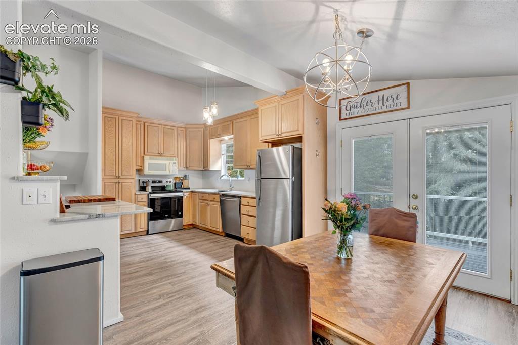Image 9 of 44: Open-concept kitchen and dining area featuring light wood-finish cabinetry,
