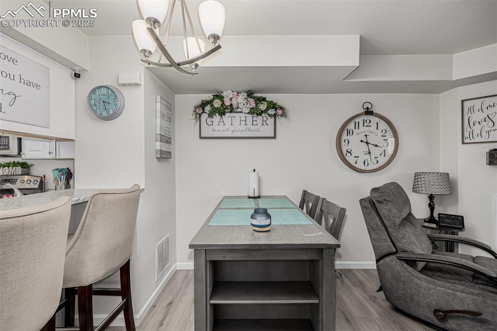 Image 13 of 47: Dining area featuring a chandelier and light wood-type flooring