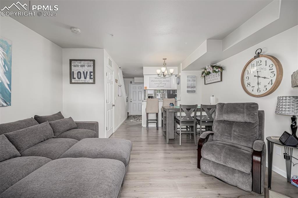 Image 15 of 47: Living room featuring light wood finished floors and a chandelier