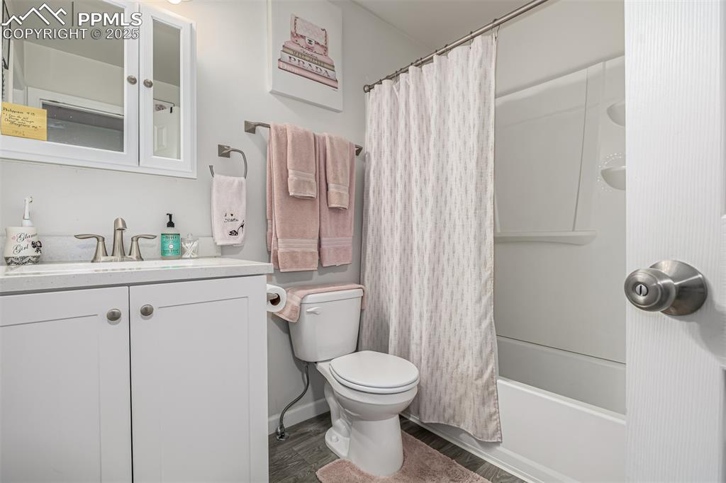 Image 18 of 47: Full bath with shower / bath combination with curtain, vanity, and dark woo