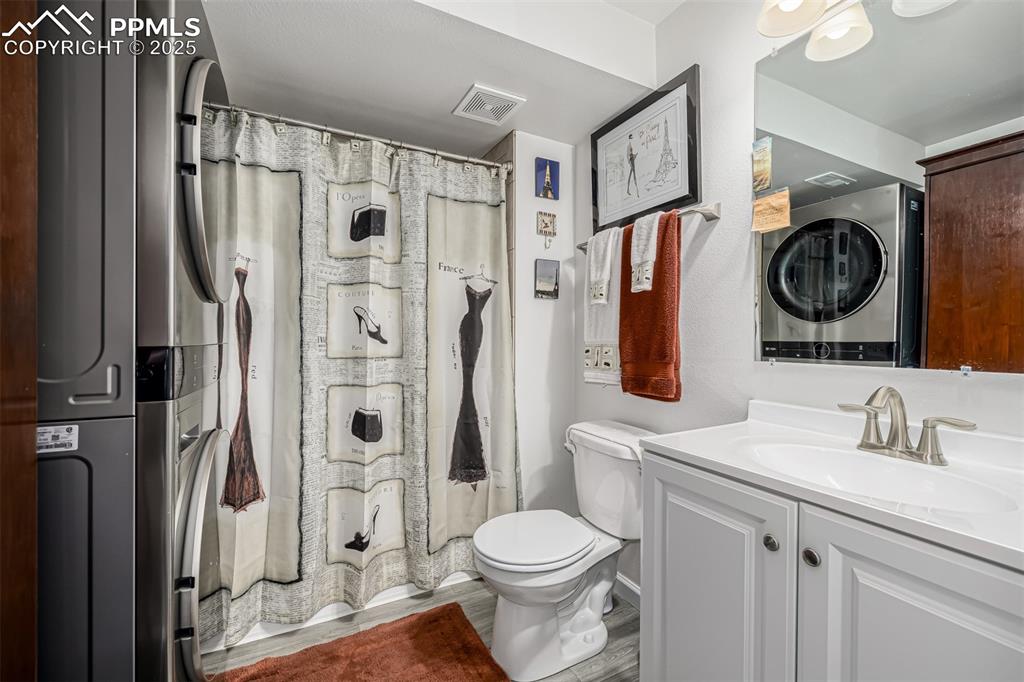 Image 22 of 47: Full bath with vanity, wood finished floors, and stacked washer and clothes