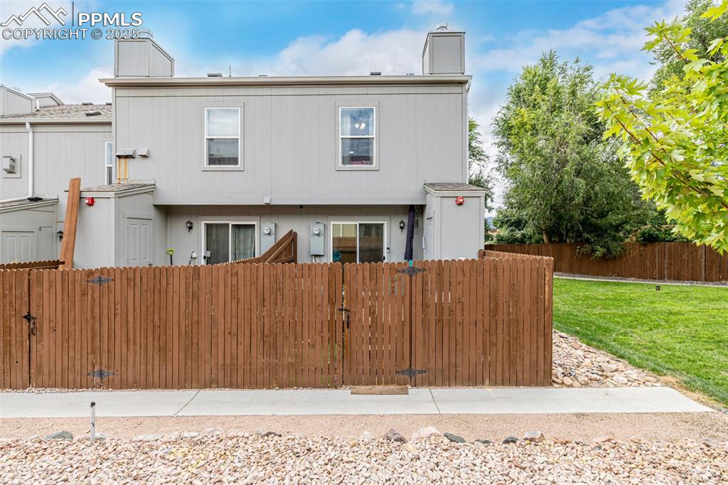 Image 47 of 47: Rear view of house with a fenced front yard, a gate, and a chimney