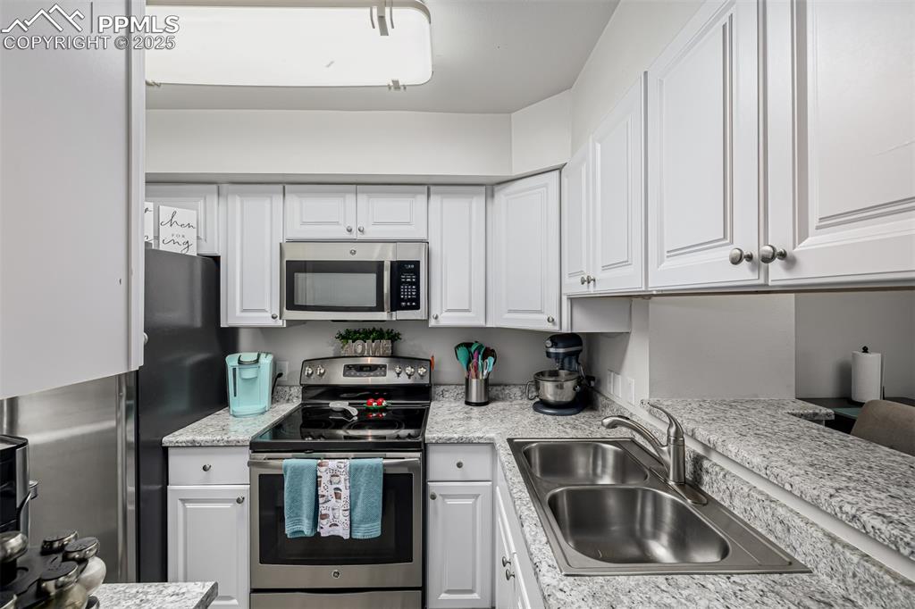 Image 8 of 47: Kitchen featuring appliances with stainless steel finishes and white cabine