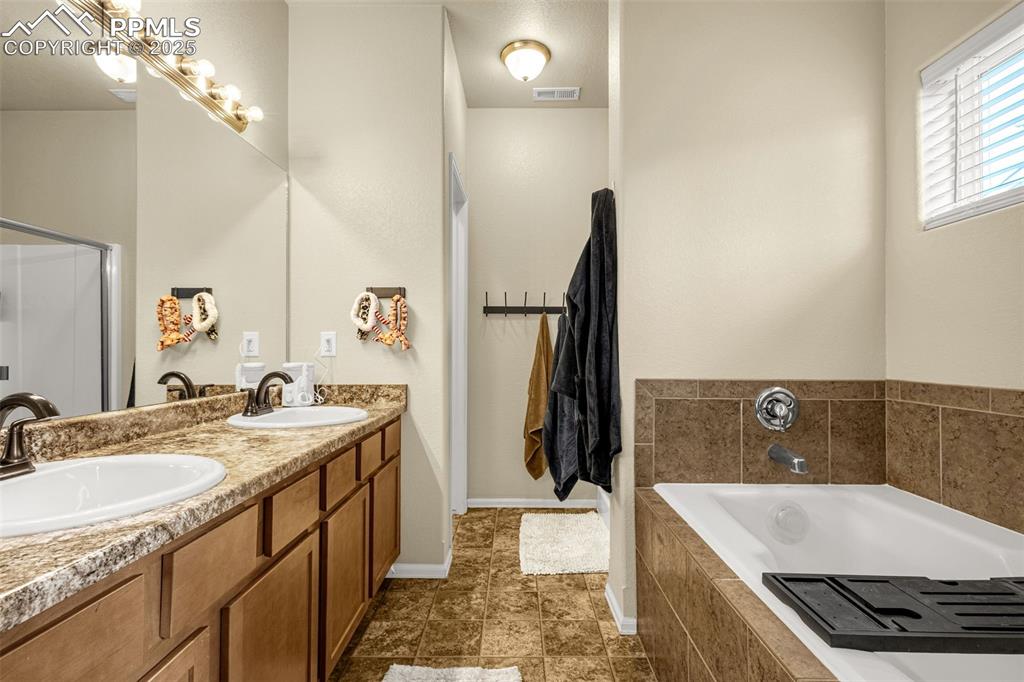 Image 19 of 31: Primary bathroom offers dual sinks, soaking tub, stand alone shower and WC.