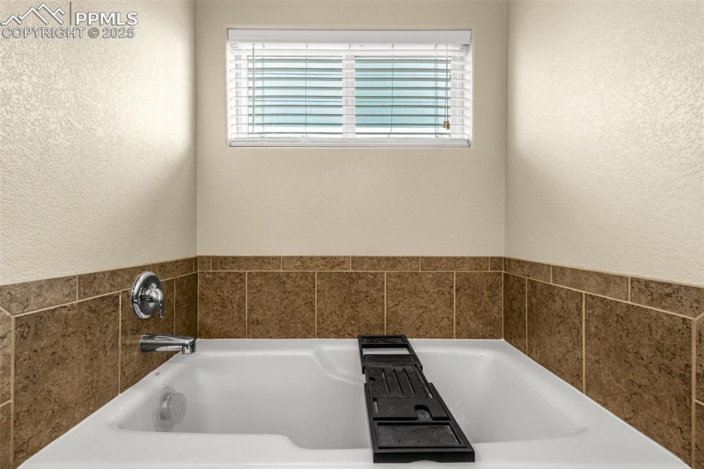 Image 20 of 31: Relax in the large tub with tile surround.  Perfect way to end the day. 
