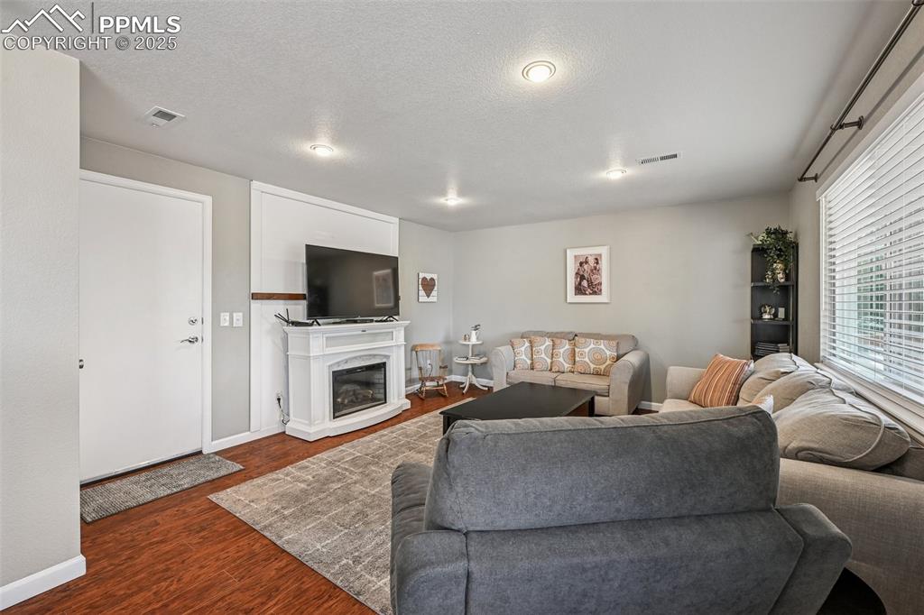 Image 13 of 38: Living area with wood finished floors, a glass covered fireplace, and a tex