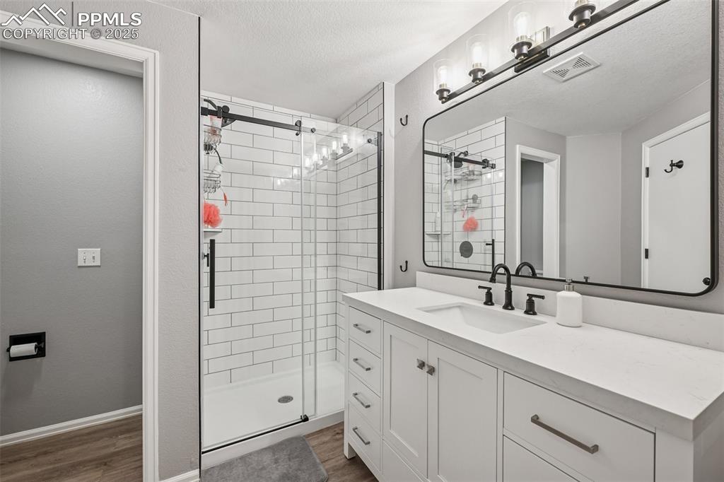 Image 16 of 38: Bathroom featuring vanity, a shower stall, dark wood finished floors, and a