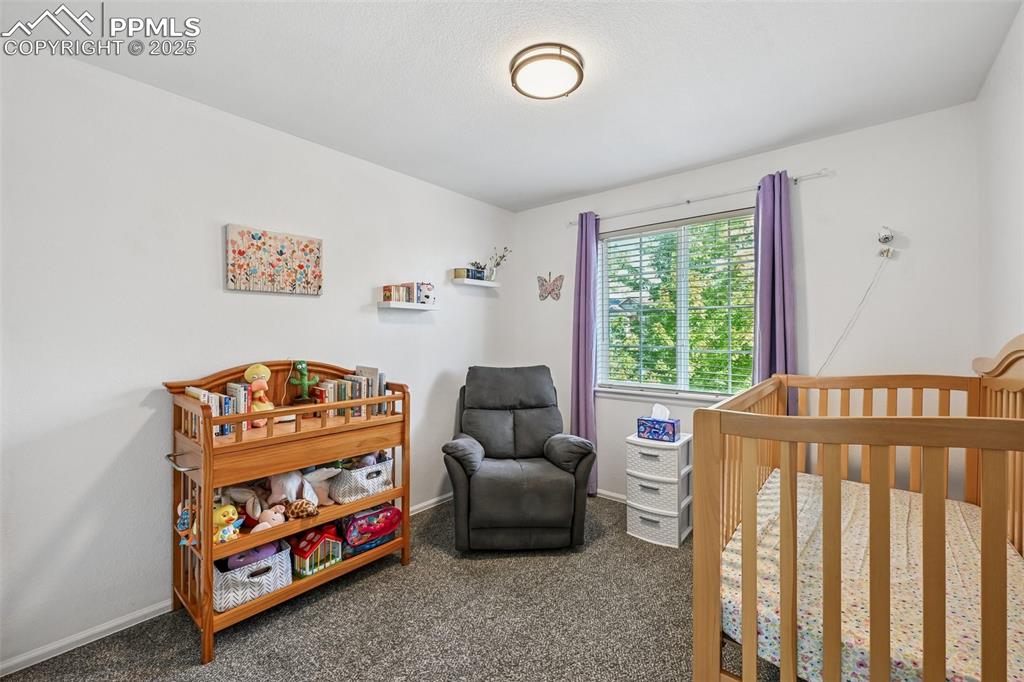 Image 18 of 38: Carpeted bedroom featuring a nursery area and baseboards