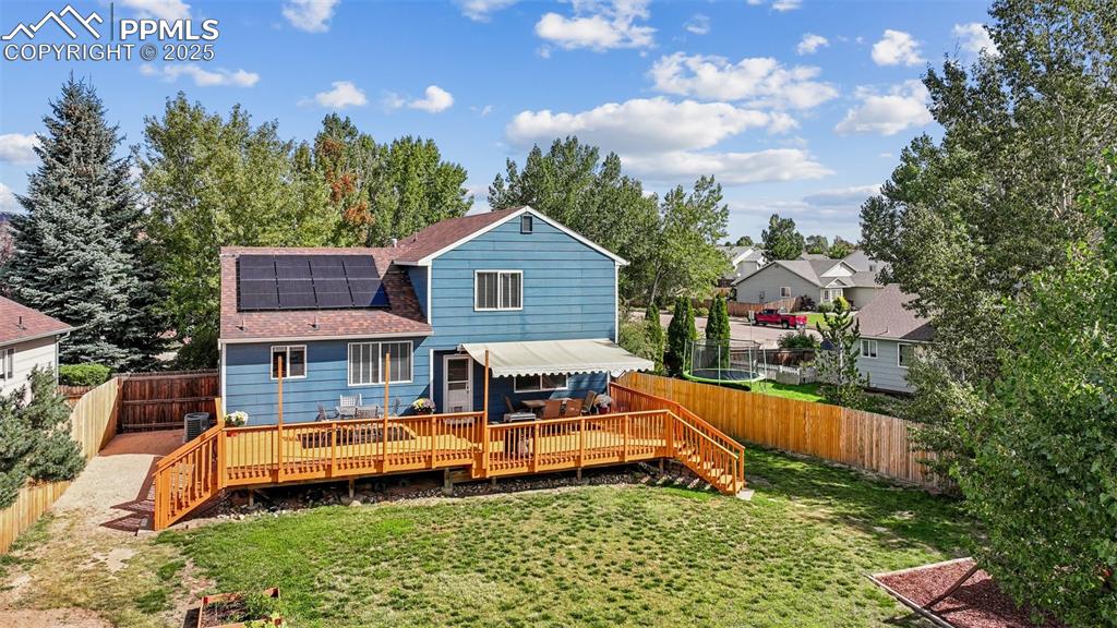 Image 2 of 38: Rear view of property with a shingled roof, a wooden deck, roof mounted sol