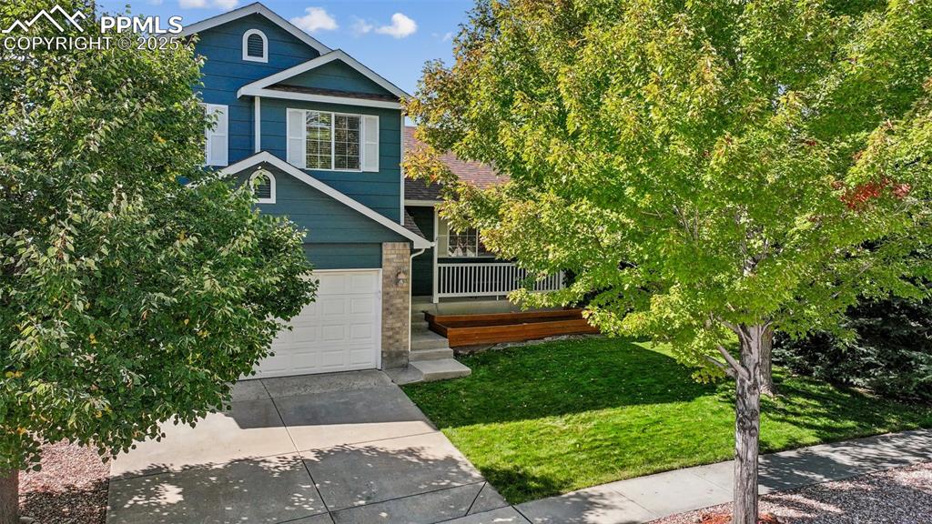 Image 28 of 38: View of front of house with a front yard, a wooden deck, concrete driveway,
