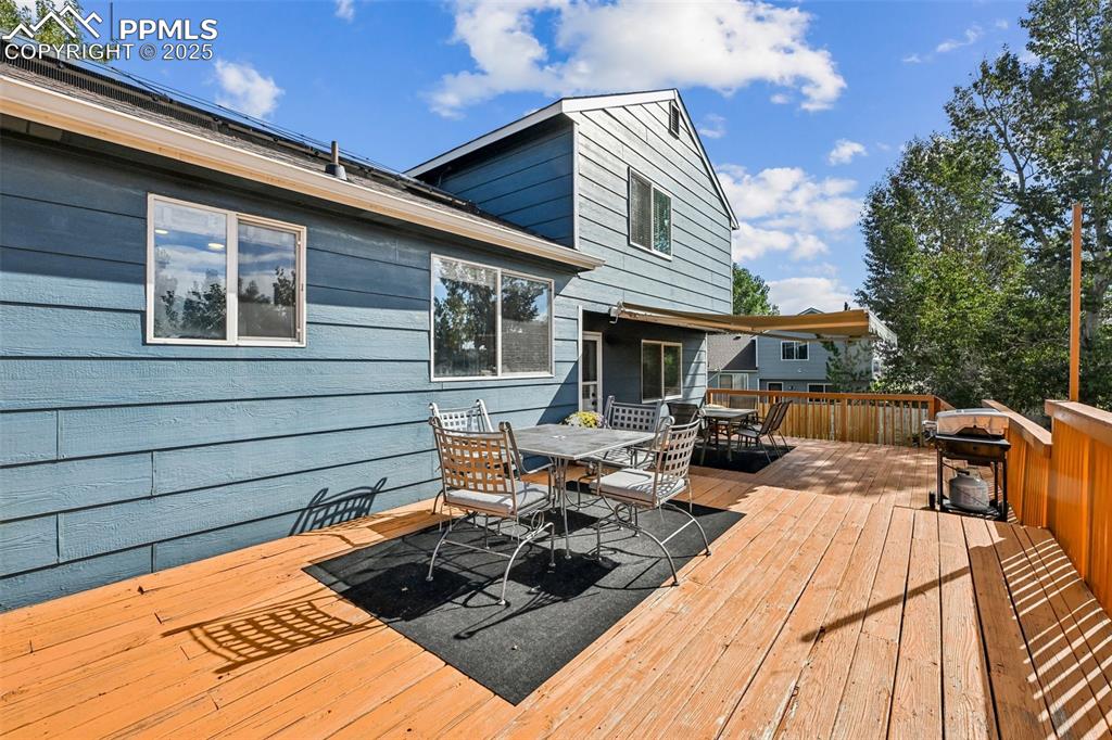 Image 31 of 38: Wooden terrace with outdoor dining area and a grill