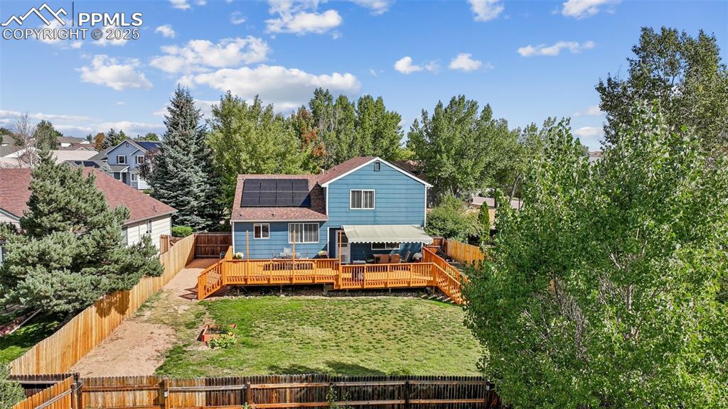 Image 34 of 38: Rear view of property with solar panels, a fenced backyard, a wooden deck, 