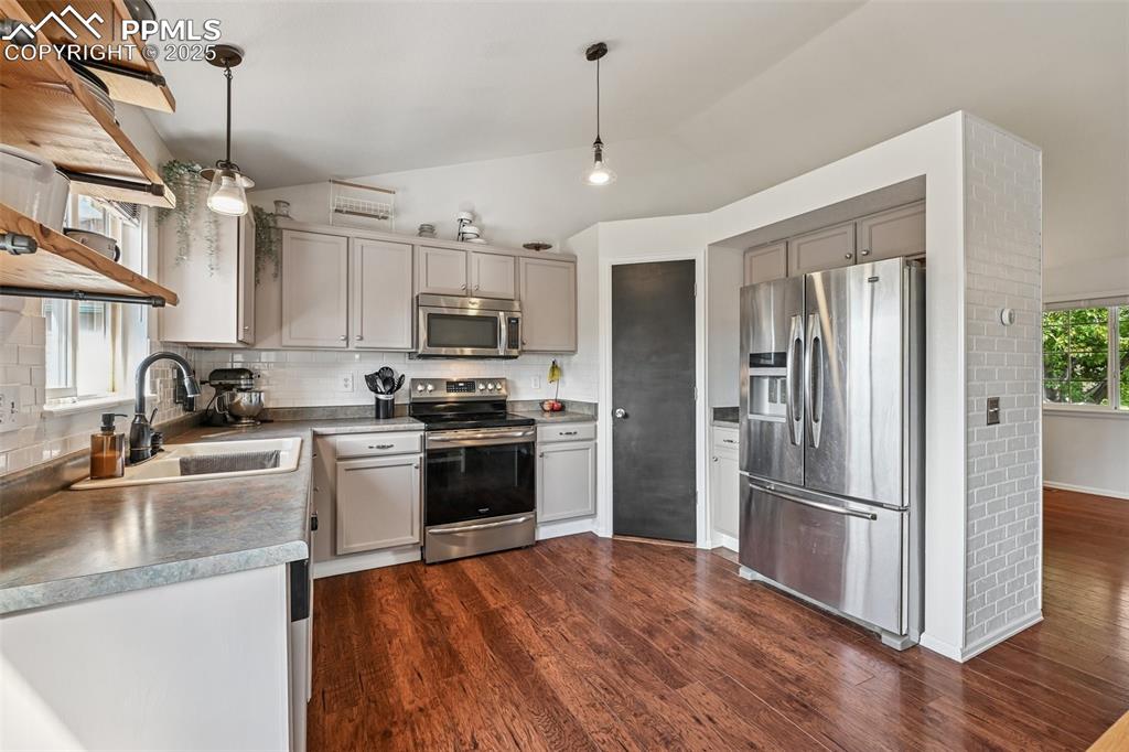 Image 4 of 38: Kitchen with appliances with stainless steel finishes, lofted ceiling, deco