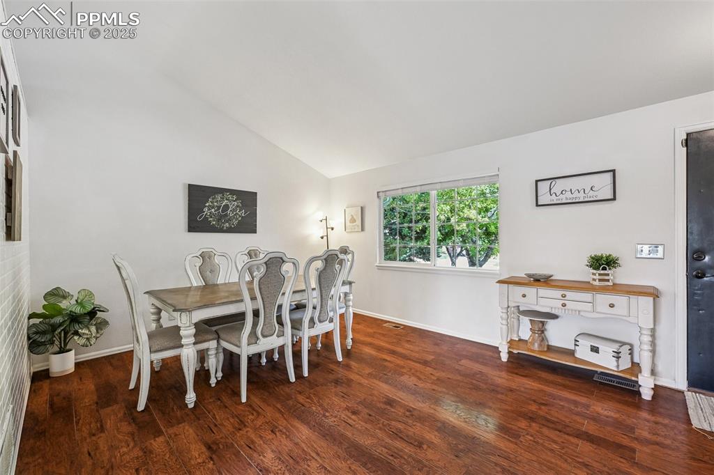 Image 5 of 38: Dining room featuring dark wood-type flooring and high vaulted ceiling