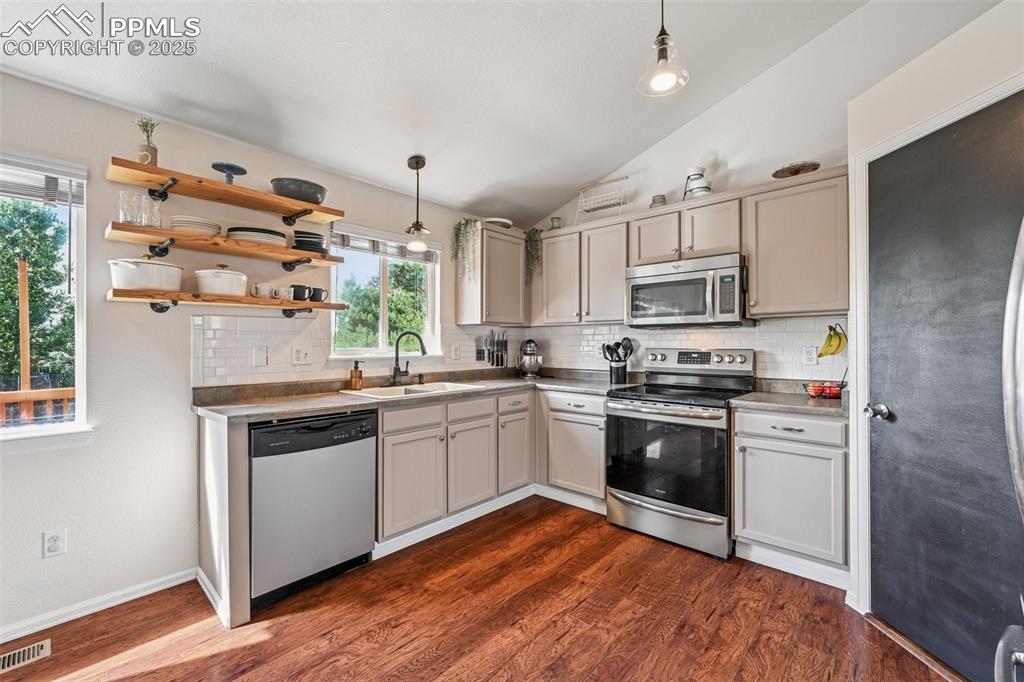 Image 7 of 38: Kitchen with vaulted ceiling, appliances with stainless steel finishes, dec